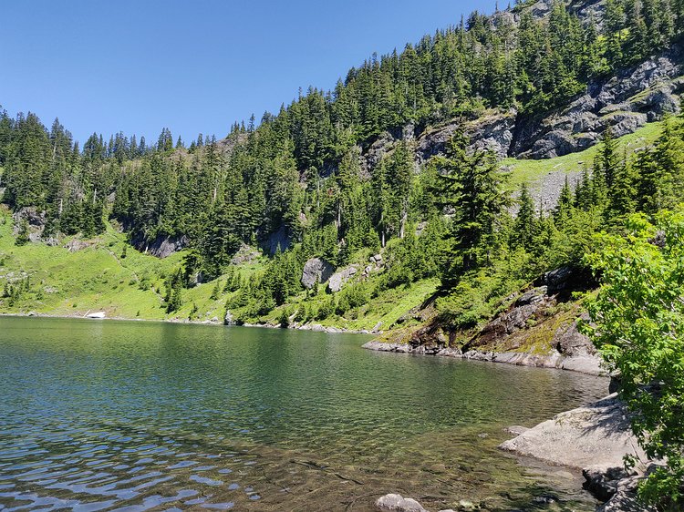 2019-07-20 13.36.42 The shoreline of the pretty Lake Lillian with the trail visible heading up the avalanche chute.